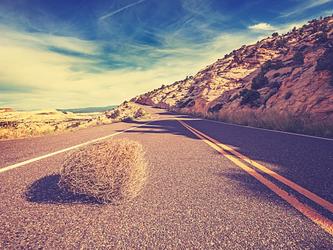 tumbleweed on an empty remote coastal road framed by hills